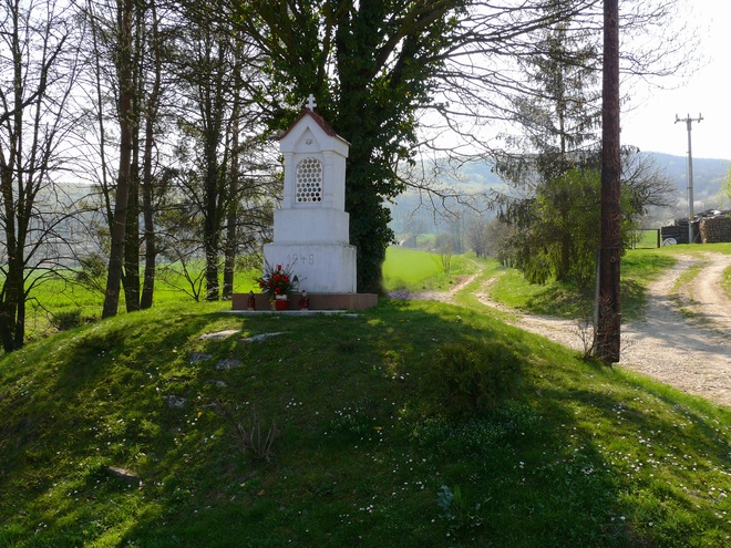 Wayside shrine on a pillar with Pietà (Maria with dead Christ on her lap) with the year date 1949; erected at the site of an earlier Baroque building on an artificial elevation at the border of the Nitra part of Kostolany, at the outlet of the former Road from the municipality of Jelenec (Gýmeš) to Gýmeš Castle across Sedlo pod Studeným hradom 