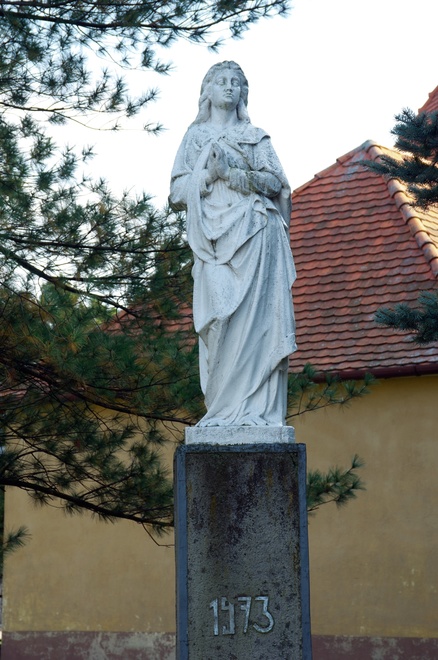 Socha Panny Márie na podstavci s vročením 1973 pri vstupe do areálu kostola zo severu
